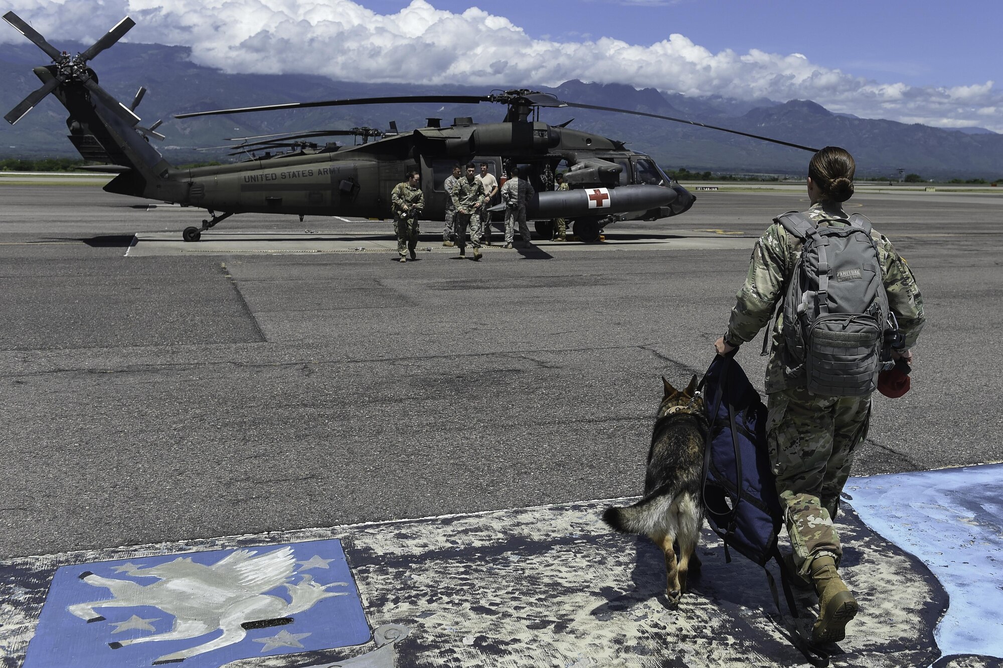 U.S. Army Spc. Mariah Ridge, a military working dog handler assigned to Joint Task Force-Bravo’s Joint Security Forces, and her MWD, Jaska, walk toward a UH-60L Black Hawk during K9 hoist evacuation training at Soto Cano Air Base, Honduras, August 15, 2016. To get the dogs familiarized with the aircraft, their handlers brought them around the helicopter and sat with them inside while the blades were turning.