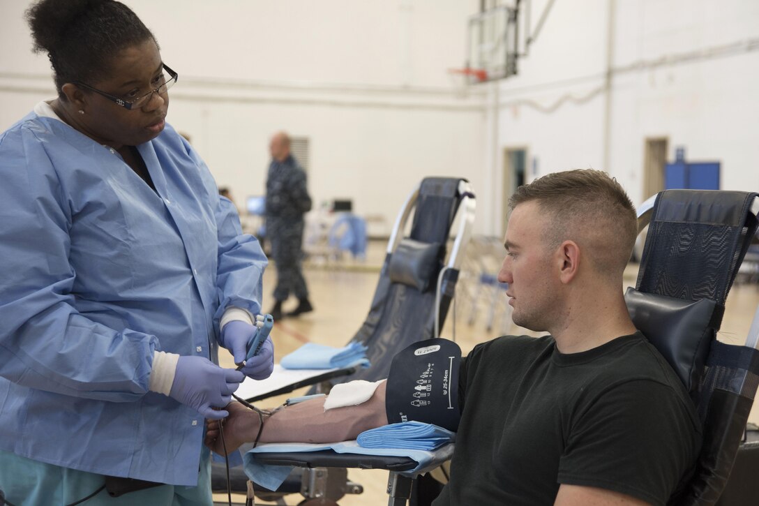 Antilnette Hunter, Walter Reed National Medical Center health technician, talks to Staff Sgt. Tim Rowland, 811th Security Forces Squadron protective services supervisor, as he donates blood at the West Fitness Center on Joint Base Andrews, Md., Aug. 16, 2016.  The Armed Services Blood Program collected blood donations that will be shipped into theater and to medical treatment facilities around the National Capital Region.