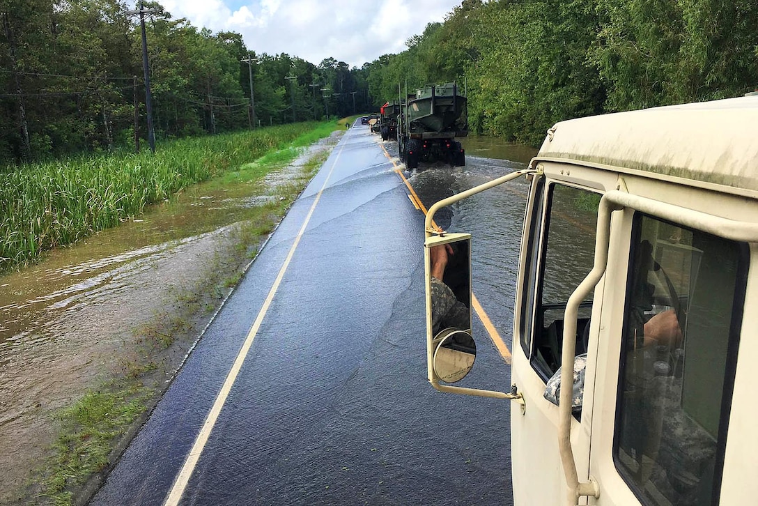 Soldiers travel in tactical vehicles to a boat launch before conducting door-to-door search and rescue missions amid severe flooding near Maurepas, La., Aug. 17, 2016. Army National Guard photo by 1st Sgt. Paul C. Meeker 