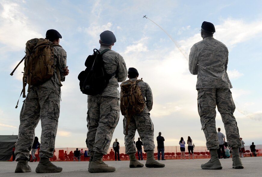 Members from the 5th Security Forces Squadron watch an aircraft practice acrobatic maneuvers during the Northern Neighbors Day practice show at Minot Air Force Base, N.D., Aug. 12, 2016. The air show was the first one in seven years and featured several demonstrations from both civilian and military aircraft. (U.S. Air Force photo by Staff Sgt. Chad Trujillo)