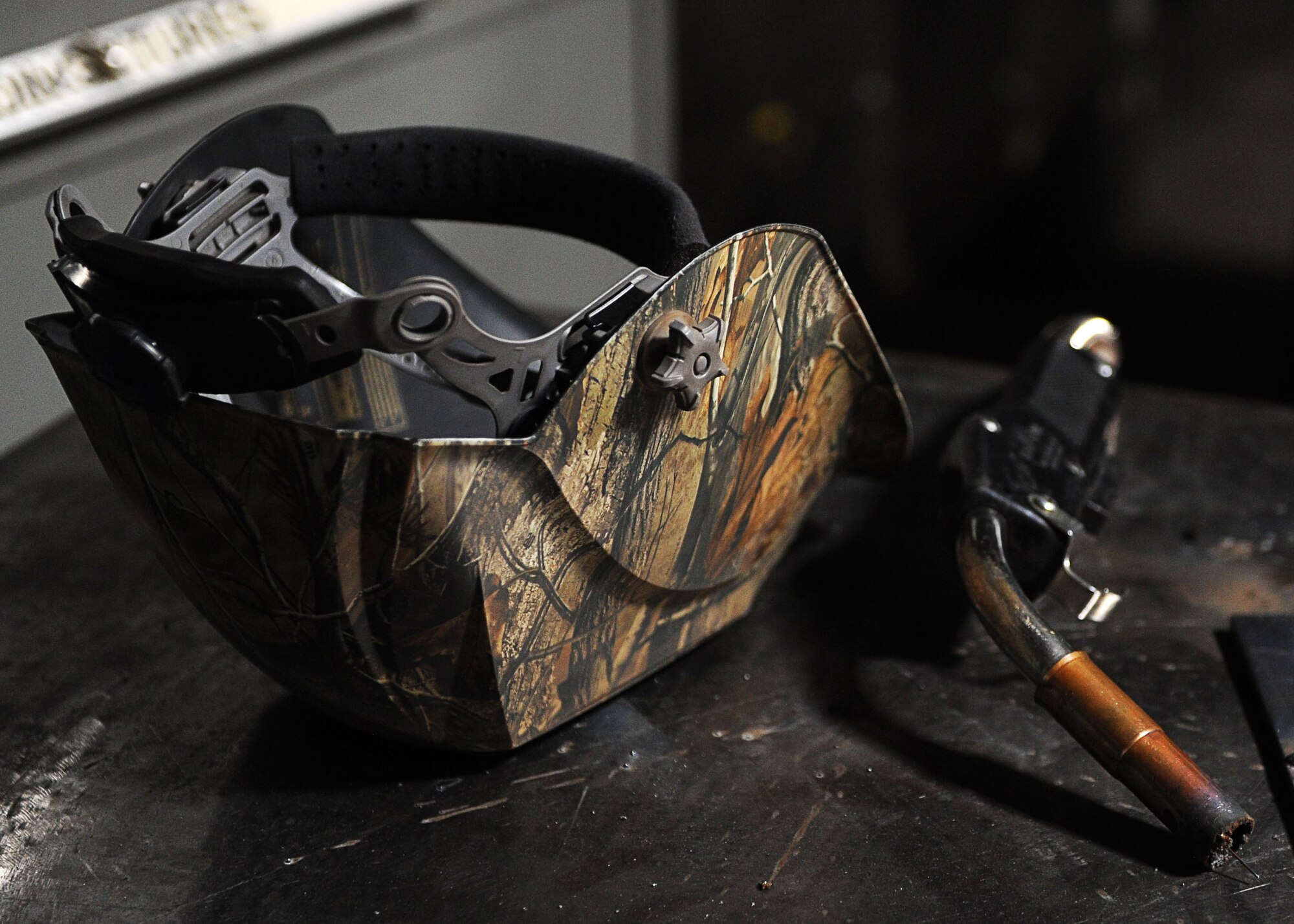 A welding helmet and wire feed welder gun sit on a table at the fabrication shop at Minot Air Force Base, N.D., Aug. 18, 2016. The 5th Maintenance Squadron fabrication flight design, weld, fabricate and locally manufacture tools for components and assemblies essential to aerospace weapon systems and related support equipment. (U.S. Air Force photo/Senior Airman Kristoffer Kaubisch)
