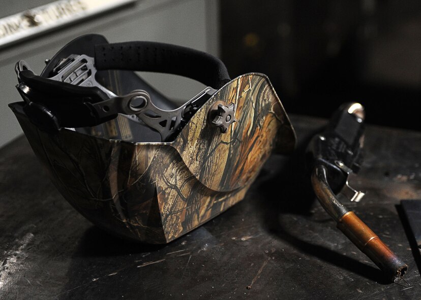 A welding helmet and wire feed welder gun sit on a table at the fabrication shop at Minot Air Force Base, N.D., Aug. 18, 2016. The 5th Maintenance Squadron fabrication flight design, weld, fabricate and locally manufacture tools for components and assemblies essential to aerospace weapon systems and related support equipment. (U.S. Air Force photo/Senior Airman Kristoffer Kaubisch)