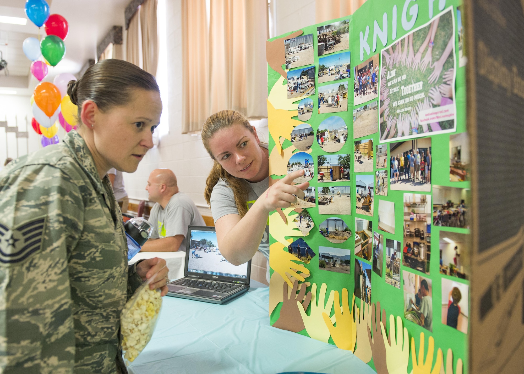 Tech. Sgt. Jennifer, the Non-Commissioned Officer In-Charge of Emergency Management, listens to Staff Sgt. Ashley, a sensor operator from the 9th Attack Squadron here, shows pictures of the project her team, The Knights, did during the Big Give as part of the Big Give after-party August 12, 2016 at Holloman Air Force Base, N.M. Over the course of three weeks, 32 teams of 412 participants spent nearly 5,000 man hours volunteering in the local community — saving the area $202,092.33. (Last names are being withheld due to operational requirements. U.S. Air Force photo by Airman 1st Class Randahl J. Jenson)