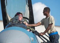 U.S. Air Force Senior Airman Christopher Tidline, a 354th Maintenance Squadron aircrew egress technician who is cross-utilized as a crew chief with the 354th Aircraft Maintenance Squadron, prepares Royal Canadian Air Force Capt. Michael Walker, an 18th Aggressor Squadron pilot, for a sortie Aug. 17, 2016, during RED FLAG-Alaska 16-3 at Eielson Air force Base, Alaska. This exercise provides unique opportunities to integrate various forces into joint, coalition and multilateral training from simulated forward operating bases. (U.S. Air Force photo by Staff Sgt. Shawn Nickel)
