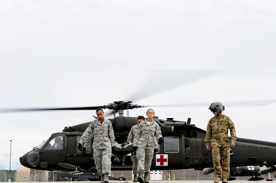 U.S. Air Force Airmen assigned to the 354th Medical Operations Squadron at Eielson Air Force Base, Alaska, transport a simulated casualty from a U.S. Army UH-60 Black Hawk helicopter during joint training Aug. 12, 2016, outside Hangar 6 at Ladd Army Airfield on Fort wainwright, Alaska. The height of the people carrying the casualty should be properly distributed to keep the simulated casualty safe as they are transported from the helicopter. (U.S. Air Force photo by Airman Isaac Johnson)
