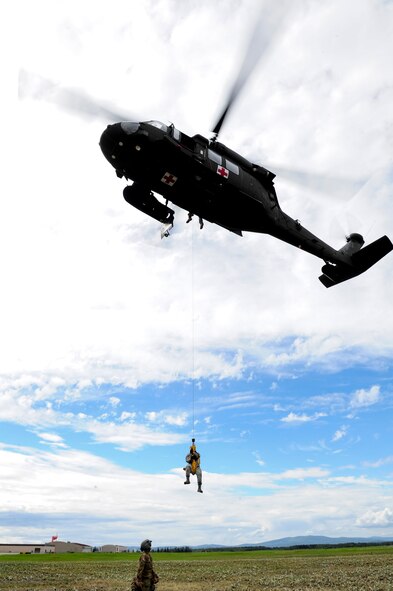 U.S. Air Force Senior Airman Roxanne Lawrence, a 354th Medical Operations Squadron nurse technician, assigned to Eielson Air Force Base, Alaska hovers under a U.S. Army UH-60 Black Hawk helicopter during medical evacuation training Aug. 12, 2016, outside Hangar 6 on Ladd Army Airfield at Fort Wainwright, Alaska. The hoist on this helicopter can carry more than 450 pounds, which allows medical personnel to bring casualties onto a hovering aircraft. (U.S. Air Force photo by Airman Isaac Johnson)

