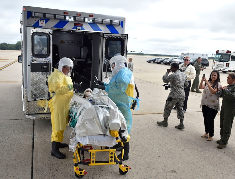 Paramedics from Walter Reed National Military Medical Center load Major Stephanie La Pierre, the patient simulating a potential exposure to Ebola and individual mobilization augmentee to the Air Mobility Command surgeon general command surgeon's office medical readiness division, into an ambulance for Exercise Mobility Solace at Joint Base Andrews, Md., Aug. 16, 2016. Mobility Solace provides Air Mobility Command, working with joint partners, the opportunity to evaluate the protocols and operational sequences of moving multiple patients exposed or infected with Ebola using the TIS, while also minimizing the risks to aircrew, medical attendants and the airframe. The TIS is a modular, scalable system, composed of at least one isolation pallet for patient transportation and care, one pallet configured as an antechamber to provide medical members with an enclosed space to safely decontaminate and remove their personal protective equipment before exiting. (U.S. Air Force Photo/Airman Megan Munoz)