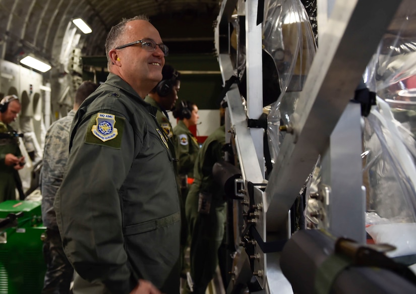 Brig. Gen. Lee Payne observes the aeromedical crew inside a Transportation Isolation System (TIS) on a C-17 Globemaster III aircraft flying to Joint Base Andrews during Exercise Mobulity Solace, Aug. 16, 2016.Mobility Solace provides Air Mobility Command, working with joint partners, the opportunity to evaluate the protocols and operational sequences of moving multiple patients exposed or infected with Ebola using the TIS, while also minimizing the risks to aircrew, medical attendants and the airframe. The TIS is a modular, scalable system, composed of at least one isolation pallet for patient transportation and care, one pallet configured as an antechamber to provide medical members with an enclosed space to safely decontaminate and remove their personal protective equipment before exiting. (U.S. Air Force Photo/Airman Megan Munoz)
