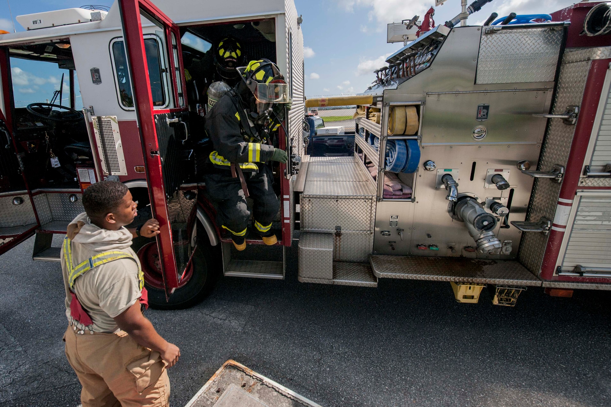 Firefighters from the 18th Civil Engineer Squadron exit a fire engine during a tower evacuation drill Aug. 15, 2016, at Kadena Air Base, Japan. Firefighters train on a regular basis in order to maintain constant readiness for emergencies. (U.S. Air Force photo by Senior Airman Peter Reft)
