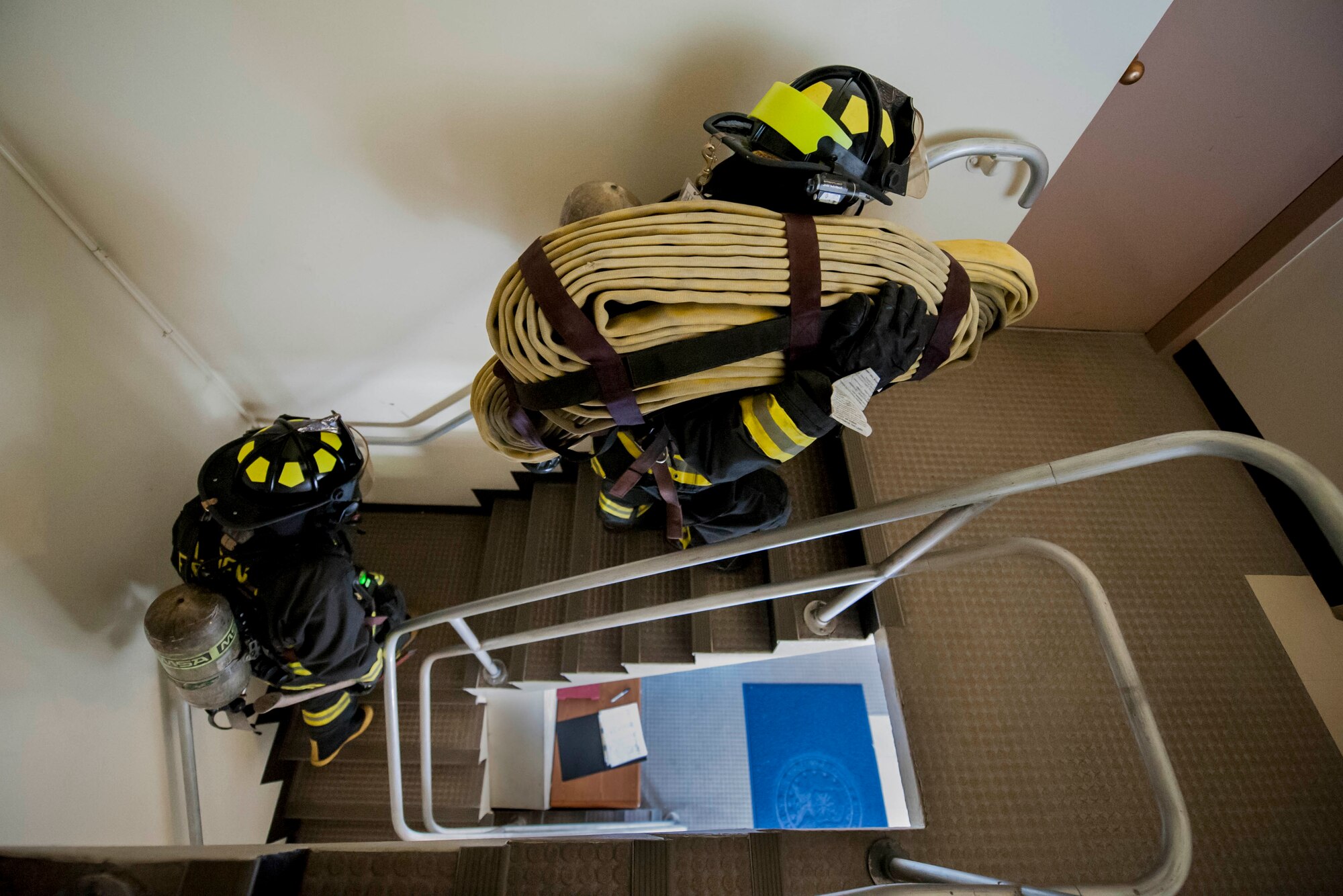 Yoshimi Sakurai and Senior Airman Brandon Hudson, 18th Civil Engineer Squadron firefighters, ascend a stairwell during a tower evacuation drill Aug. 15, 2016, at Kadena Air Base, Japan. Sakurai and Hudson carried hoses and tools up 13 flights of stairs to reach the top where simulated victims needed to be evacuated and carried out to safety. (U.S. Air Force photo by Senior Airman Peter Reft)