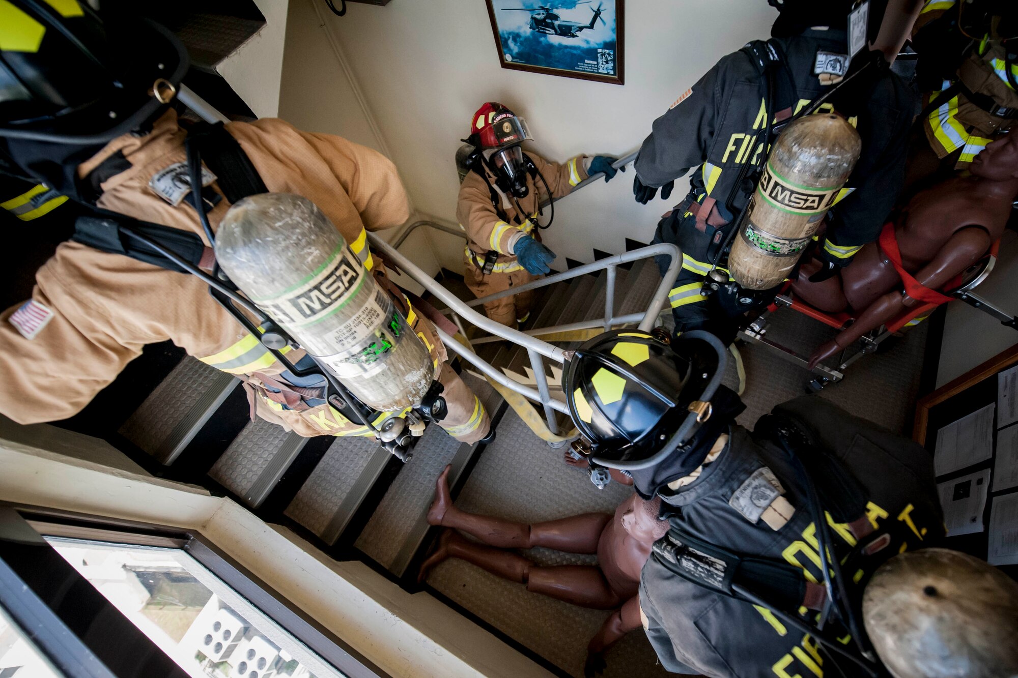 Firefighters of the 18th Civil Engineer Squadron perform a personnel recovery down a stairwell during a tower evacuation drill Aug. 15, 2016, at Kadena Air Base, Japan. The tower drill enabled firefighters to become familiar with the layout of the structure, involving cramped spaces offering little room for maneuvering personnel and equipment. (U.S. Air Force photo by Senior Airman Peter Reft)