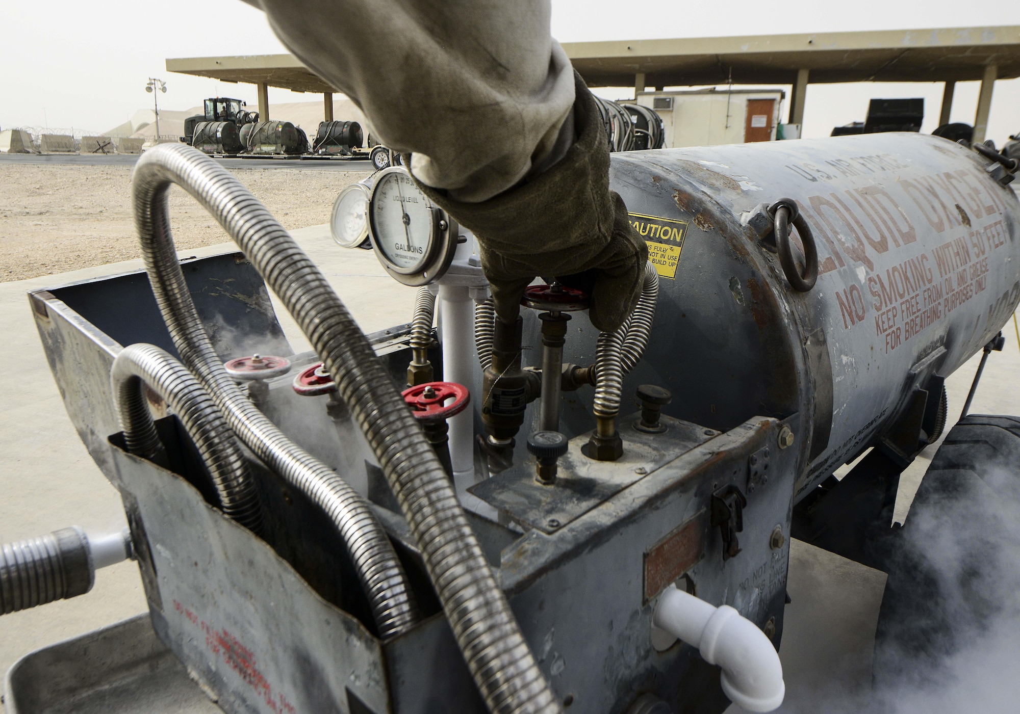 Senior Airman Donte Hatcher, 379th Expeditionary Logistics Readiness Squadron fuels cryogenic operator, opens the vent valve of a 50-gallon liquid oxygen tank during an inspection Aug. 5, 2016, at Al Udeid Air Base, Qatar. The cryogenics team supplies, receives and issues liquid oxygen and liquid nitrogen tanks to 11 bases within the U.S. Air Forces Central Command’s area of responsibility. (U.S. Air Force photo/Senior Airman Janelle Patiño/Released)
