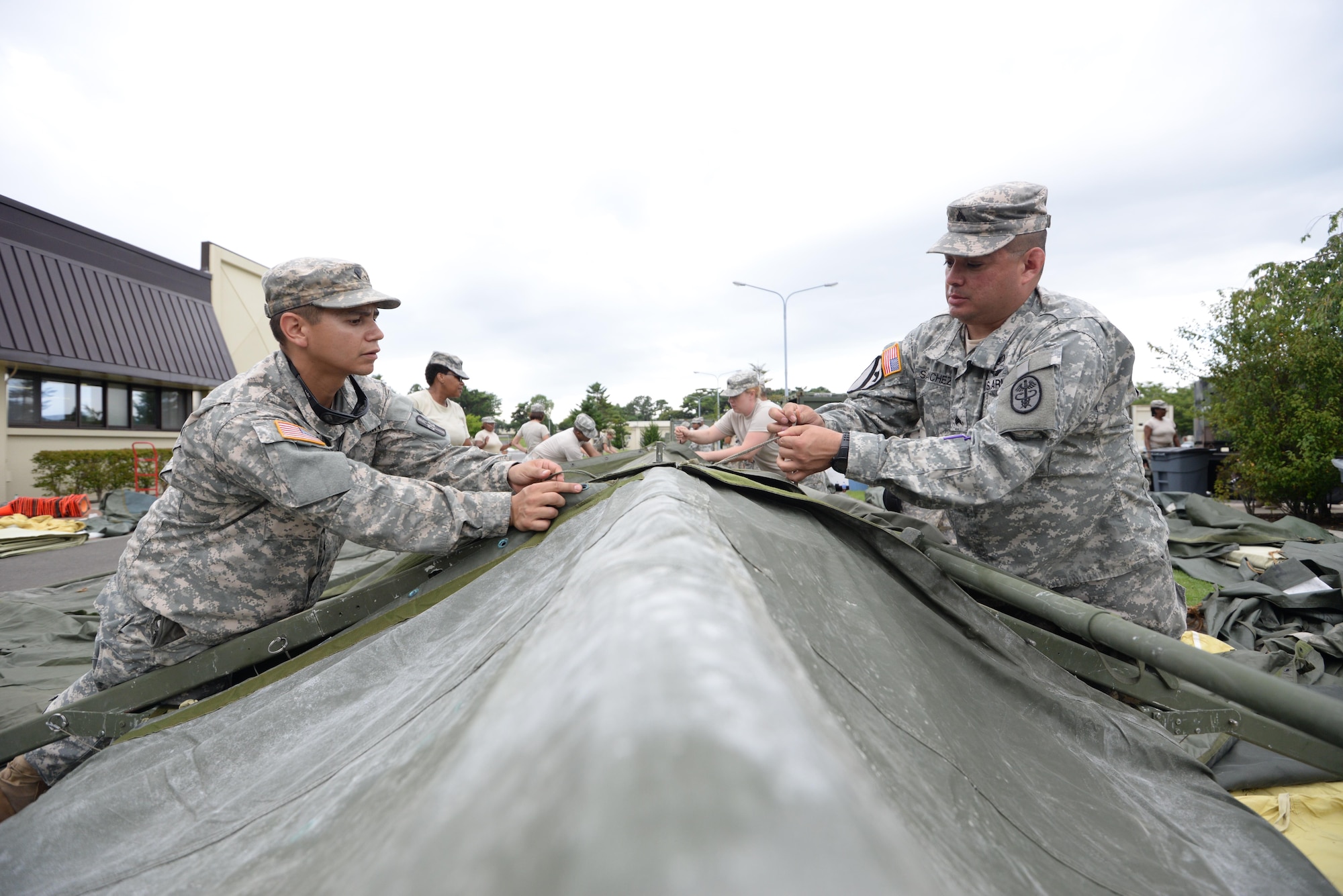 U.S. Army Spc. Dwight Chavez (left), 228th Combat Support Hospital preventive medicine specialist, and Sgt. Randy Sanchez (right), 228th CSH healthcare sergeant, construct a tent in support of a medical exercise being held at Misawa Air Base, Japan, Aug. 18, 2016. The 228th CSH will be conducting joint exercises over the course of a week with the 35th Medical Group from Misawa AB. (U.S. Air Force photo by Senior Airman Jarrod Vickers) 