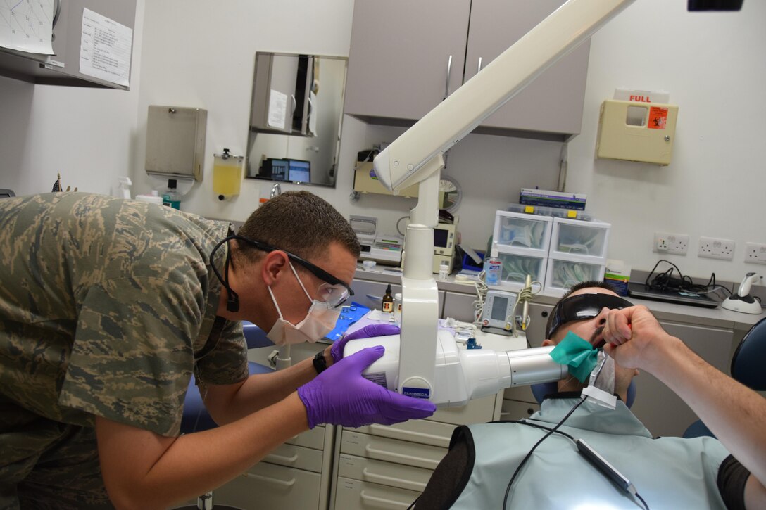 Sgt. Shane Hinton (left), 379th Expeditionary Medical Group dental technician, lines up his x-ray to make an image of a tooth belonging to Senior Airman Jordan Thompson, 379th Expeditionary Logistics Readiness Squadron, July 30, 2016, Al Udeid Air Base, Qatar. Hinton was taking the x-ray for Maj. (Dr.) Benjamin Gantt to check on the status of a root canal they were finishing on Thompson. (U.S. Air Force photo/Technical Sgt. Carlos J. Treviño/Release)