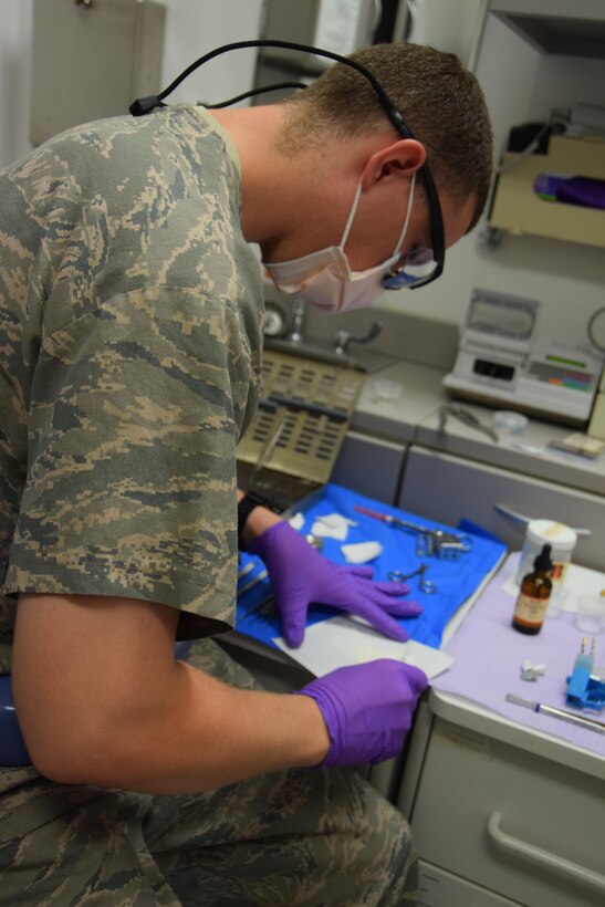 Sgt. Shane Hinton, 379th Expeditionary Medical Group dental technician,  mixes sealant for Maj. (Dr.) Benjamin Gantt to place inside a root canal on Senior Airman Jordan Thompson, 379th Expeditionary Logistics Readiness Squadron, July 30, 2016, Al Udeid Air Base, Qatar. The abundance of sugary energy drinks consumed here is a cause of tooth decay and dental visits according to Maj. Gantt. (U.S. Air Force photo/Technical Sgt. Carlos J. Treviño/Release)