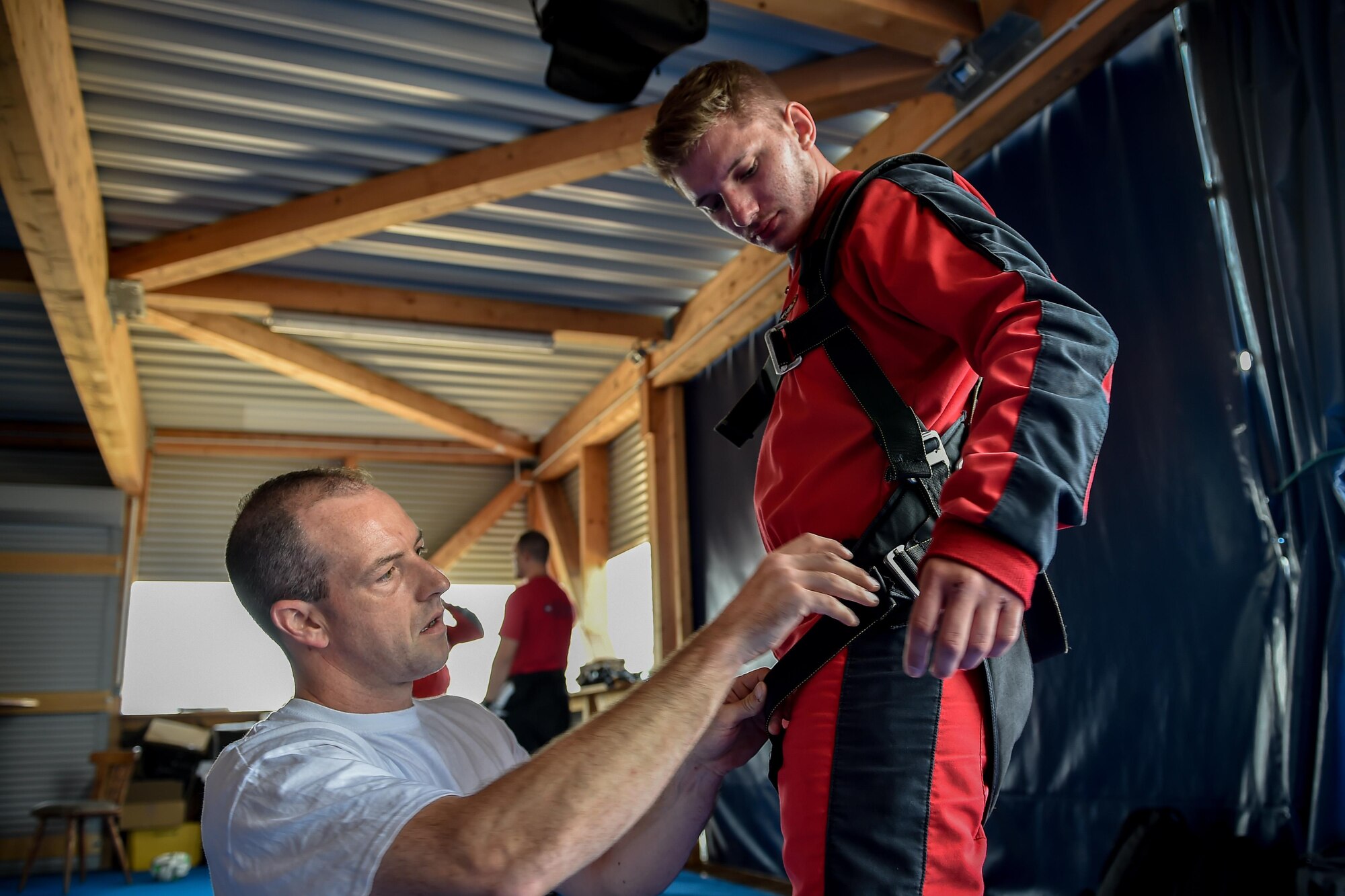 A skydiving instructor prepares a harness for Airman 1st Class Rocco Guanella, 435th Contingency Response Squadron member, before a tandem jump over Wallerfangen, Germany, Aug. 13, 2016. Comprehensive Airman Fitness is paramount in ensuring members are mission ready at all times. Fifteen Airmen received the opportunity to skydive to build on the spiritual foundation that keeps them prepared. (U.S. Air Force photo/Senior Airman Nicole Keim)