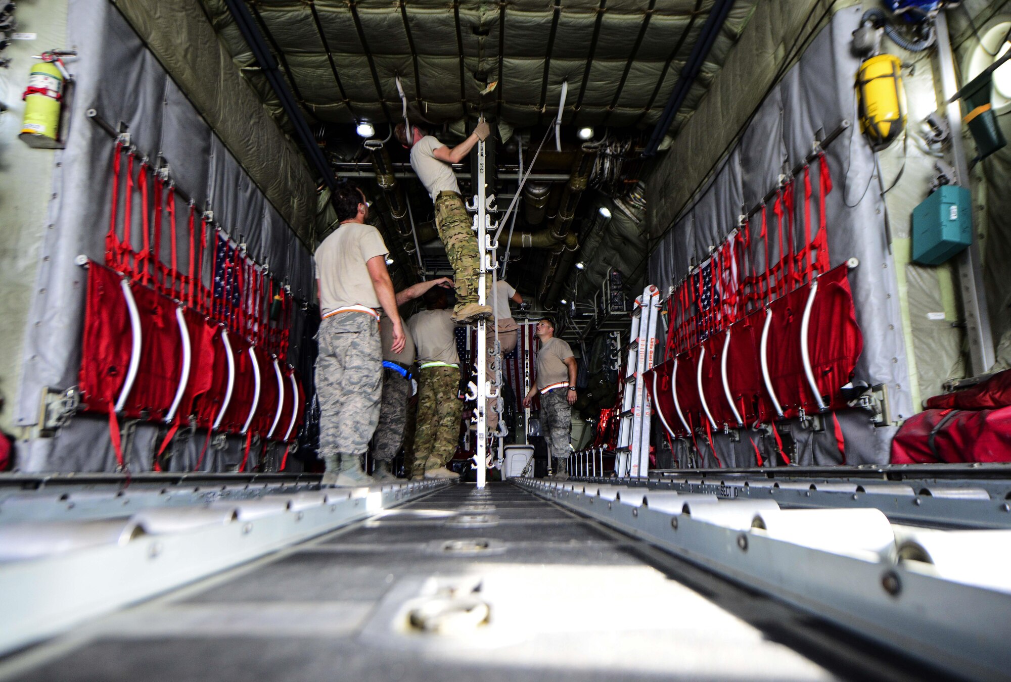 Airmen from the 746th Expeditionary Airlift Squadron and 746th Expeditionary Aircraft Maintenance Unit set up the C-130 Hercules prior to cargo and passengers arriving July 28, 2016, at Al Udeid Air Base, Qatar. The aeromedical equipment team along with the aeromedical evacuation operations team configures the aircraft prior to every mission by setting up the stations and dropping the straps for incoming patients and equipment to be stored during the flight. (U.S. Air Force photo/Senior Airman Janelle Patiño/Released)