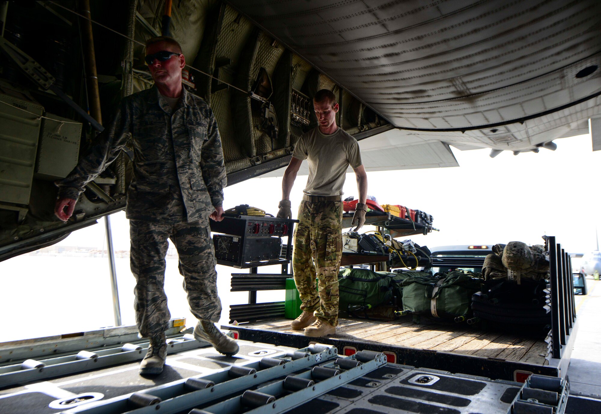 Senior Master Sgt. Lesley Blue, 746th Expeditionary Airlift Squadron first sergeant, and 1st Lt. Justin Stein, 379th Expeditionary Aeromedical Evacuation Squadron medical crew director, load a frequency converter onto a C-130 Hercules July 28, 2016, at Al Udeid Air Base, Qatar. A frequency converter is used to convert the air conditioning power to household grade power so that in-flight equipment can be charged and used during the mission. (U.S. Air Force photo/Senior Airman Janelle Patiño/Released)