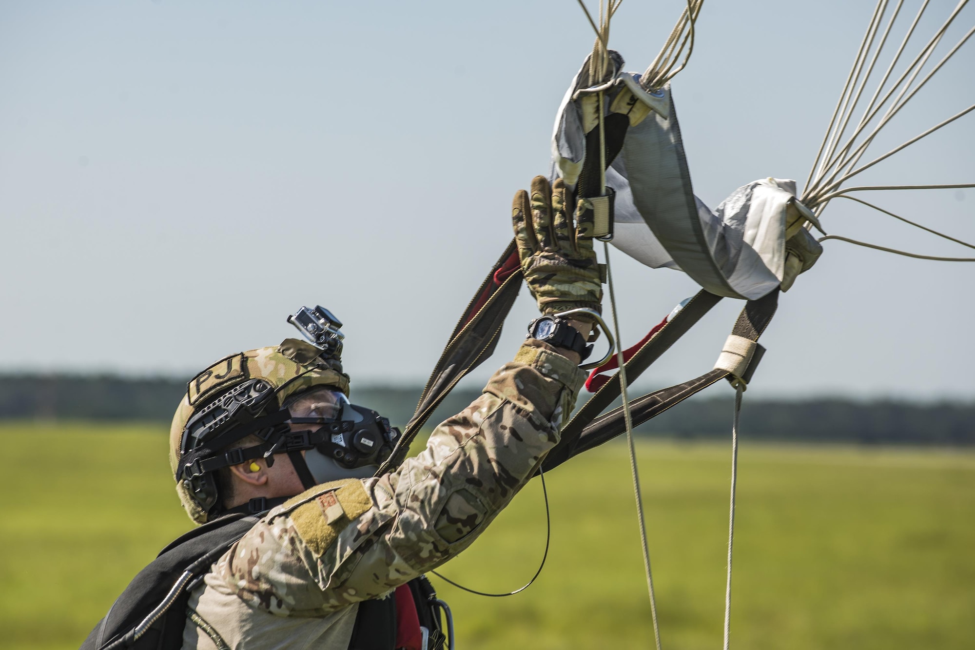 U.S. Air Force Master Sgt. Christian Egger, 347th Rescue Group pararescueman, collects his parachute after landing from a high-altitude, low-opening jump, Aug. 18, 2016, at Moody Air Force Base, Ga. During operations at high altitudes, crewmembers are required to breathe 100 percent pure oxygen to combat the lowered oxygen levels present. (U.S. Air Force photo by Airman 1st Class Daniel Snider)