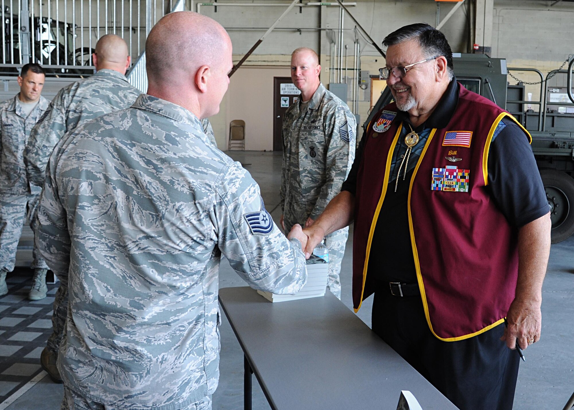 Tech. Sgt. Daniel Cary, 319th Contracting Flight contracting officer, shakes hands with Capt. William “Bill” Robinson, United States Air Force retired, August 18, 2016, on Grand Forks Air Force Base, N.D. Robinson signed copies of his book after speaking with Airmen about his time spent as a POW. (U.S. Air Force photo by Senior Airman Ryan Sparks/Released)