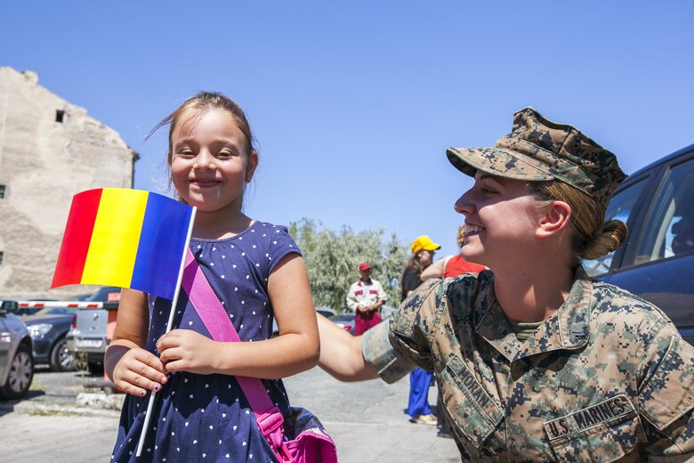 A U.S. Marine with the Black Sea Rotational Force, hands a Romanian and American flag to a girl who was pleased to see a female in uniform at the Romanian Navy Day in Constanța, Romania, Aug. 15, 2016. Marines from BSRF 16.2 were invited to the ceremony as partners and allies to maintain and strengthen our relationships so we may collectively address common security challenges in the region. Black Sea Rotational Force is an annual multilateral security cooperation activity between the U.S. Marine Corps and partner nations in the Black Sea, Balkan and Caucasus regions designed to enhance participants’ collective professional military capacity, promote regional stability and build enduring relationships with partner nations (U.S. Marine Corps photo by Cpl. Kyle C. Talbot)