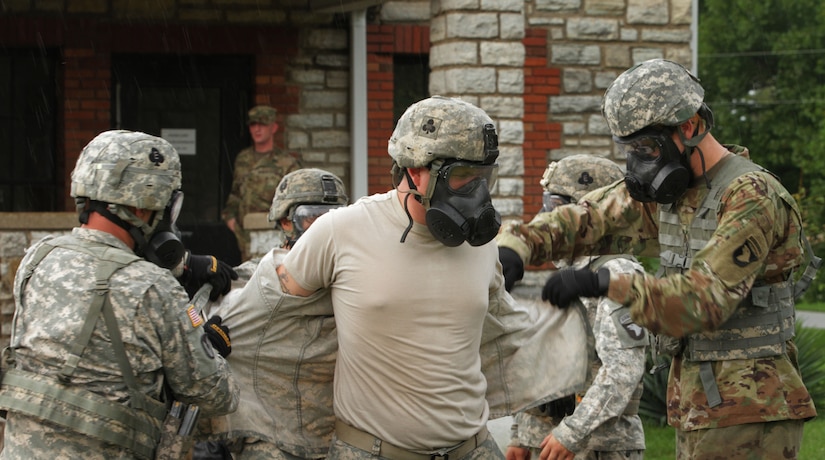 (left) Spc. Gary Allen, a wheeled vehicle mechanic, Yuba City, California native, and (right) Pfc. Joseph Kirkman, a Construction Equipment Repairer, and Greensboro, North Carolina native, both with Echo Forward Support Company, 326th Brigade Engineer Battalion, 1st Brigade Combat Team, 101st Airborne Division, Fort Campbell, Kentucky, simulate decontaminating fellow FSC Soldier, Pfc. Ashton Barrell,(Carter) a motor transport operator and Evansville, Indiana native, during a Chemical, Biological, Radiological and Nuclear Defense training exercise at Muscatatuck Urban Training Center, Indiana, Aug. 14, 2016. Company E leaders used the exercise to introduce their Soldiers to a new piece of equipment, the M50 – Joint Service General Purpose Mask, which replaced the US Military’s M40 Field Protective Mask. (US Army Reserve Photo by Sgt. Quentin Johnson, 211th MPAD/Released)