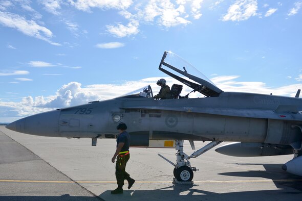Royal Canadian Air Force Cpl. Zach McCann, an aviation systems technician assigned to the 409th Tactical Fighter Squadron out of Canadian Forces Base Cold Lake, Alberta, walks around a CF-18 Hornet aircraft while Captain Chris Swartz, a pilot assigned to the same unit, prepares to take off from the Eielson Air Force Base, Alaska flight line during RED FLAG-Alaska (RF-A) 16-3,Aug. 18, 2016. RF-A provides unique opportunities to integrate various forces into joint, coalition and multilateral training from simulated forward operating bases. (U.S. Air Force photo by Airman Isaac Johnson)
