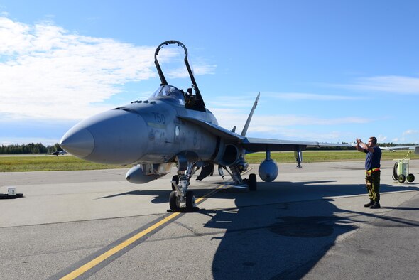 Royal Canadian Air Force Avr. Laurie Dunbar, an avionics systems technician assigned to the 409th Tactical Fighter Squadron, Canadian Forces Base Cold Lake, Alberta, communicates with Captain Yuri Mokievsky, a pilot assigned to the same unit, through hand signals during RED FLAG-Alaska (RF-A) 16-3, at Eielson Air Force Base, Alaska, Aug. 18, 2016. RF-A provides training for deployed maintenance and support personnel in sustainment of large-force deployed air operations. (U.S. Air Force photo by Airman 1st Class Cassandra Whitman)