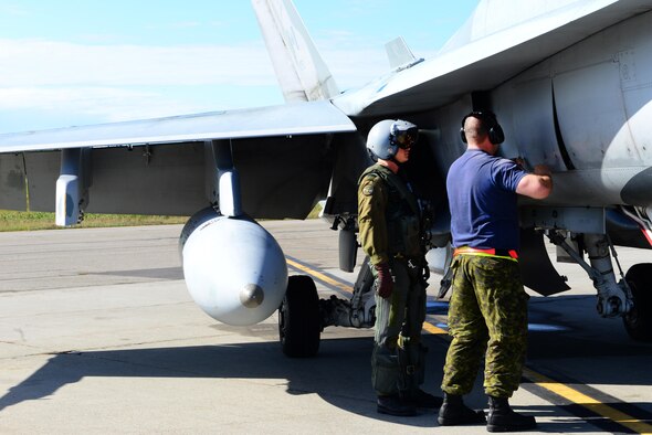 Royal Canadian Air Force Avr. Laurie Dunbar, right, an avionics systems technician, unscrews a hatch on the side of a CF-18 Hornet aircraft for Captain Yuri Mokievsky, a pilot, to review before takeoff during RED FLAG-Alaska (RF-A) 16-3, at Eielson Air Force Base, Alaska, Aug. 18, 2016. Both are assigned to the 409th Tactical Fighter Squadron, Canadian Forces Base Cold Lake, Alberta. RF-A provides training for deployed maintenance and support personnel in sustainment of large-force air operations. (U.S. Air Force photo by Airman 1st Class Cassandra Whitman)