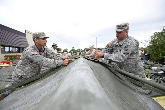 U.S. Army Spc. Dwight Chavez (left), 228th Combat Support Hospital preventive medicine specialist, and Sgt. Randy Sanchez (right), 228th CSH healthcare sergeant, construct a tent in support of a medical exercise being held at Misawa Air Base, Japan, Aug. 18, 2016. The 228th CSH will be conducting joint exercises over the course of a week with the 35th Medical Group from Misawa AB.
