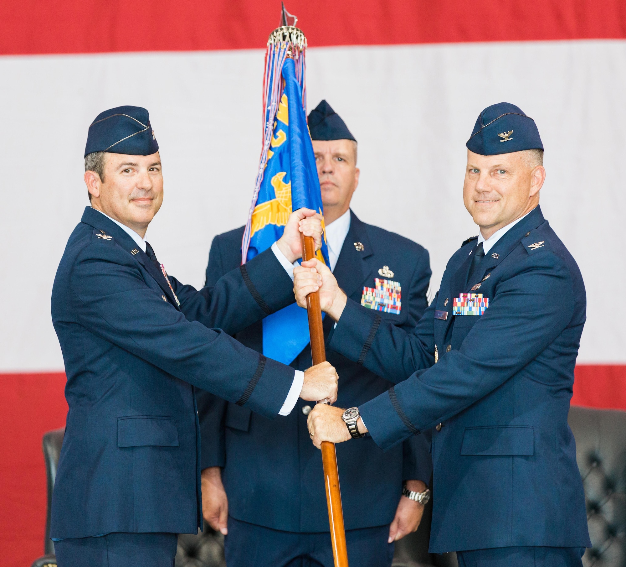 Col. David Gaedecke, 552nd Air Control Wing commander, left, passes the 552nd Maintenance Group guidon to Col. Brian Moore during a change of command ceremony held Aug. 8. Awaiting the guidon is Chief Master Sgt. Mike Phillippe, 552nd MXG superintendent. Colonel Moore succeeded Col. Andre Kennedy who retired from active duty. Colonel Moore previously served as the assistant deputy director for Joint Strategy and Plans at the Pentagon. (Air Force photo by Senior Master Sgt. Tom Edwards)