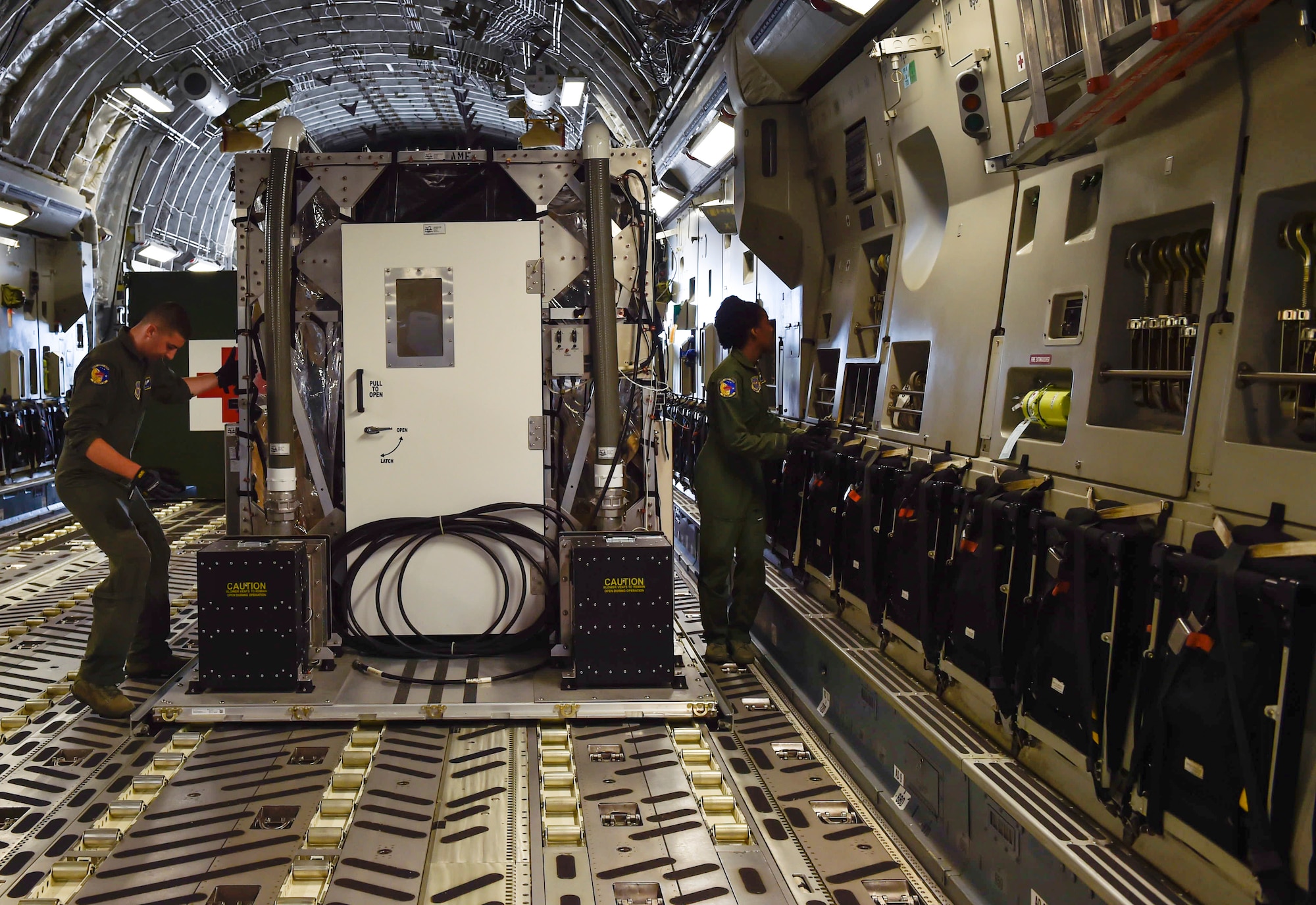 Airman Jeff McGee, a 3rd Airlift Squadron loadmaster from Dover Air Force Base, and Senior Airman Kaely Brackett, a 3rd AS loadmaster, secure a Transportation Isolation System (TIS) during Exercise Mobility Solace at Joint Base Charleston, S.C., Aug. 15, 2016. Mobility Solace provides Air Mobility Command, working with joint partners, the opportunity to evaluate the protocols and operational sequences of moving multiple patients exposed or infected with Ebola using the TIS, while also minimizing the risks to aircrew, medical attendants and the airframe. The TIS is a modular, scalable system, composed of at least one isolation pallet for patient transportation and care, one pallet configured as an "antechamber" to provide medical members with an enclosed space to safely decontaminate and remove their personal protective equipment before exiting. (U.S. Air Force Photo/Airman Megan Munoz)
