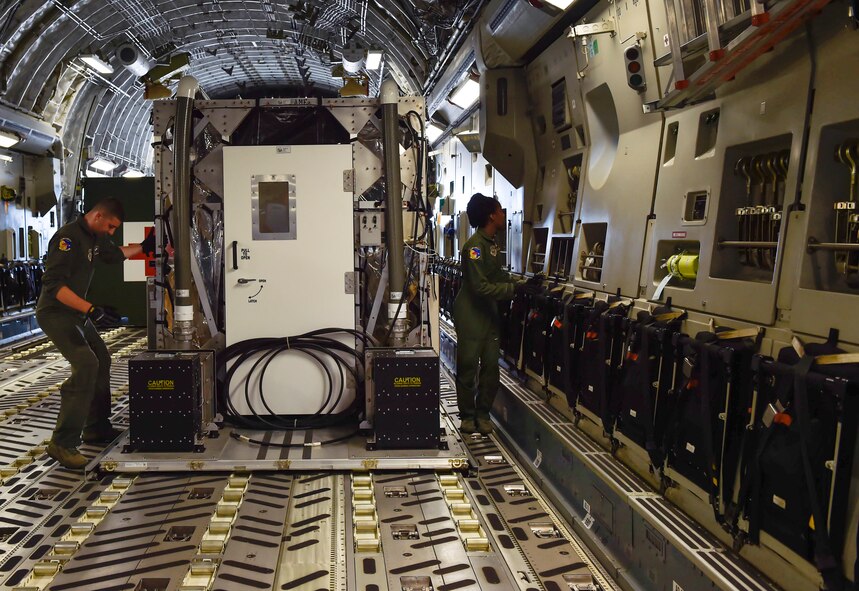 Airman Jeff McGee, a 3rd Airlift Squadron loadmaster from Dover Air Force Base, and Senior Airman Kaely Brackett, a 3rd AS loadmaster, secure a Transportation Isolation System (TIS) during Exercise Mobility Solace at Joint Base Charleston, S.C., Aug. 15, 2016. Mobility Solace provides Air Mobility Command, working with joint partners, the opportunity to evaluate the protocols and operational sequences of moving multiple patients exposed or infected with Ebola using the TIS, while also minimizing the risks to aircrew, medical attendants and the airframe. The TIS is a modular, scalable system, composed of at least one isolation pallet for patient transportation and care, one pallet configured as an "antechamber" to provide medical members with an enclosed space to safely decontaminate and remove their personal protective equipment before exiting. (U.S. Air Force Photo/Airman Megan Munoz)
