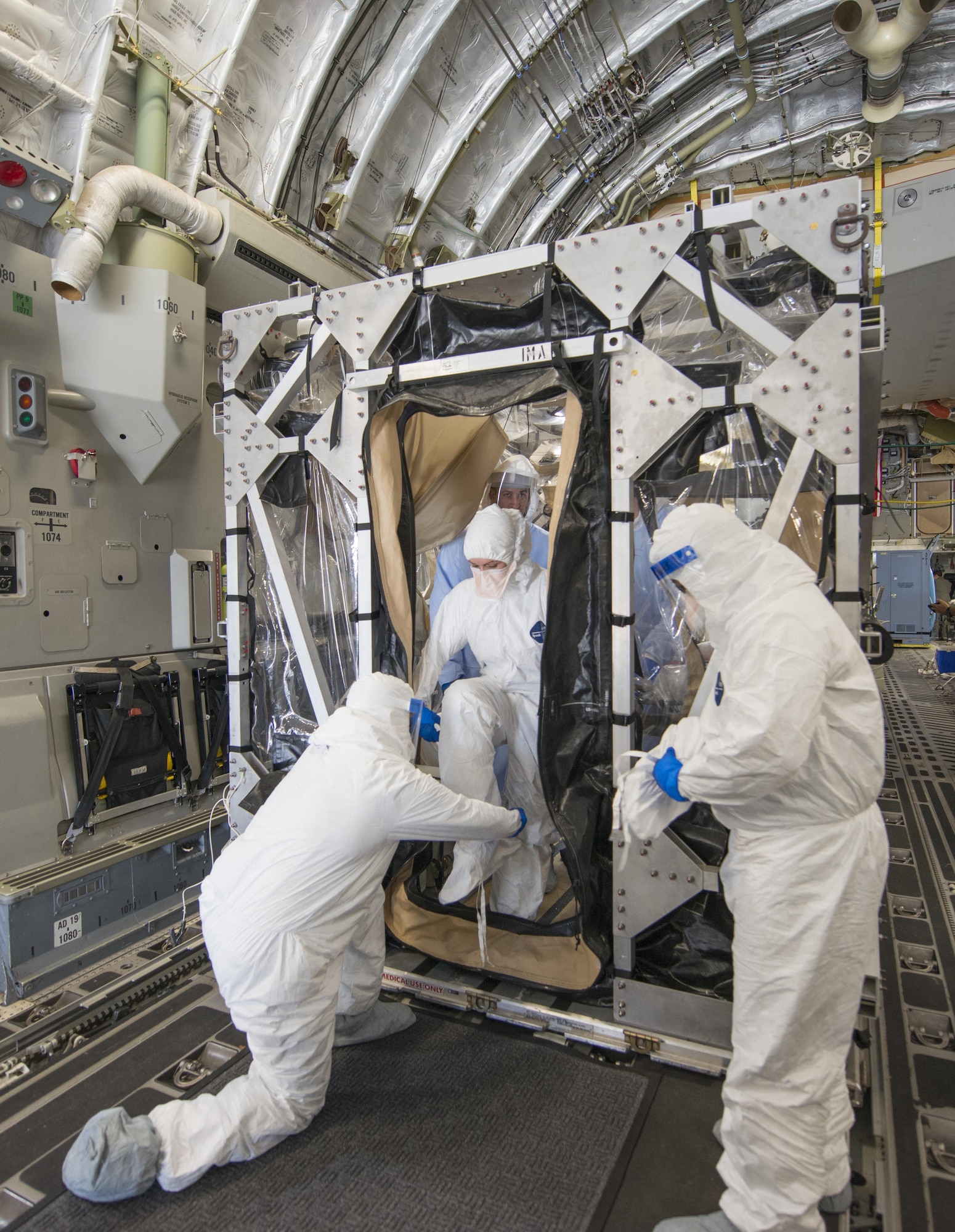 Members of the aeromedical evacuation crew help Major Stephanie La Pierre, the patient simulating a potential exposure to Ebola and individual mobilization augmentee to the Air Mobility Command surgeon general command surgeon's office medical readiness division, out of a Transportation Isolation System (TIS) during Exercise Mobility Solace at Joint Base Andrews, Md., Aug. 16, 2016. Mobility Solace provides Air Mobility Command, working with joint partners, the opportunity to evaluate the protocols and operational sequences of moving multiple patients exposed or infected with Ebola using the TIS, while also minimizing the risks to aircrew, medical attendants and the airframe. The TIS is a modular, scalable system, composed of at least one isolation pallet for patient transportation and care, one pallet configured as an "antechamber" to provide medical members with an enclosed space to safely decontaminate and remove their personal protective equipment before exiting. (U.S. Air Force Photo/Airman Megan Munoz)
