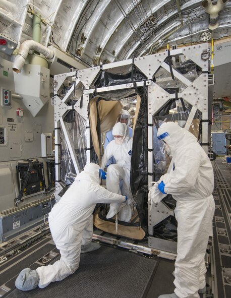 Members of the aeromedical evacuation crew help Major Stephanie La Pierre, the patient simulating a potential exposure to Ebola and individual mobilization augmentee to the Air Mobility Command surgeon general command surgeon's office medical readiness division, out of a Transportation Isolation System (TIS) during Exercise Mobility Solace at Joint Base Andrews, Md., Aug. 16, 2016. Mobility Solace provides Air Mobility Command, working with joint partners, the opportunity to evaluate the protocols and operational sequences of moving multiple patients exposed or infected with Ebola using the TIS, while also minimizing the risks to aircrew, medical attendants and the airframe. The TIS is a modular, scalable system, composed of at least one isolation pallet for patient transportation and care, one pallet configured as an "antechamber" to provide medical members with an enclosed space to safely decontaminate and remove their personal protective equipment before exiting. (U.S. Air Force Photo/Airman Megan Munoz)
