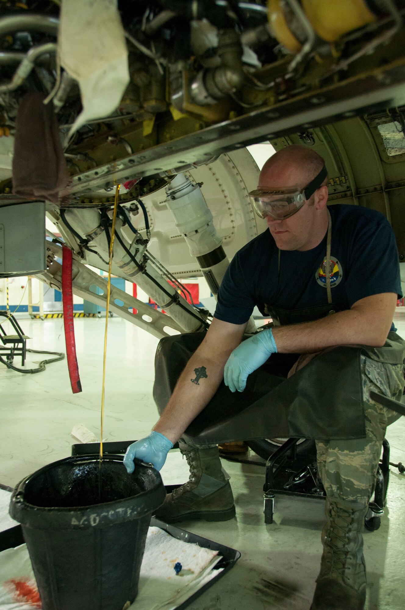 Senior Airman Trevor Kring, crew chief with the 162nd Maintenance Group, holds a bucket still under a stream of oil while emptying the oil from part of an F-16. Under the bucket is a stack of rags to catch any small spills, which will be commercially wrung to remove the oil. All of the oil that is gathered from routine maintenance or spills is collected and recycled by an outside company, and is then re-refined into motor oil. The 162nd Wing recycles more than 5,000 gallons of oil every year. (Air National Guard photo by Capt. Logan Clark)