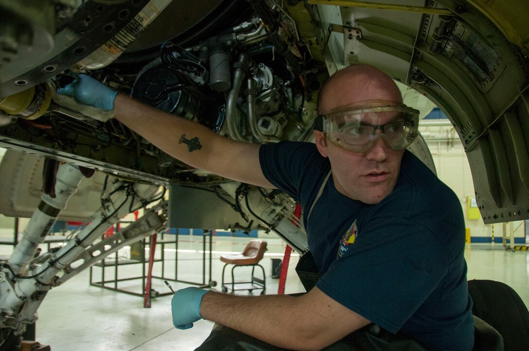 Senior Airman Trevor Kring, crew chief with the 162nd Maintenance Group, prepares to change the oil in a part of an F-16, checking with a fellow maintainer for accuracy. All of the oil that is gathered from routine maintenance or spills is collected and recycled by an outside company, and is then re-refined into motor oil. The 162nd Wing recycles more than 5,000 gallons of oil every year. (Air National Guard photo by Capt. Logan Clark)