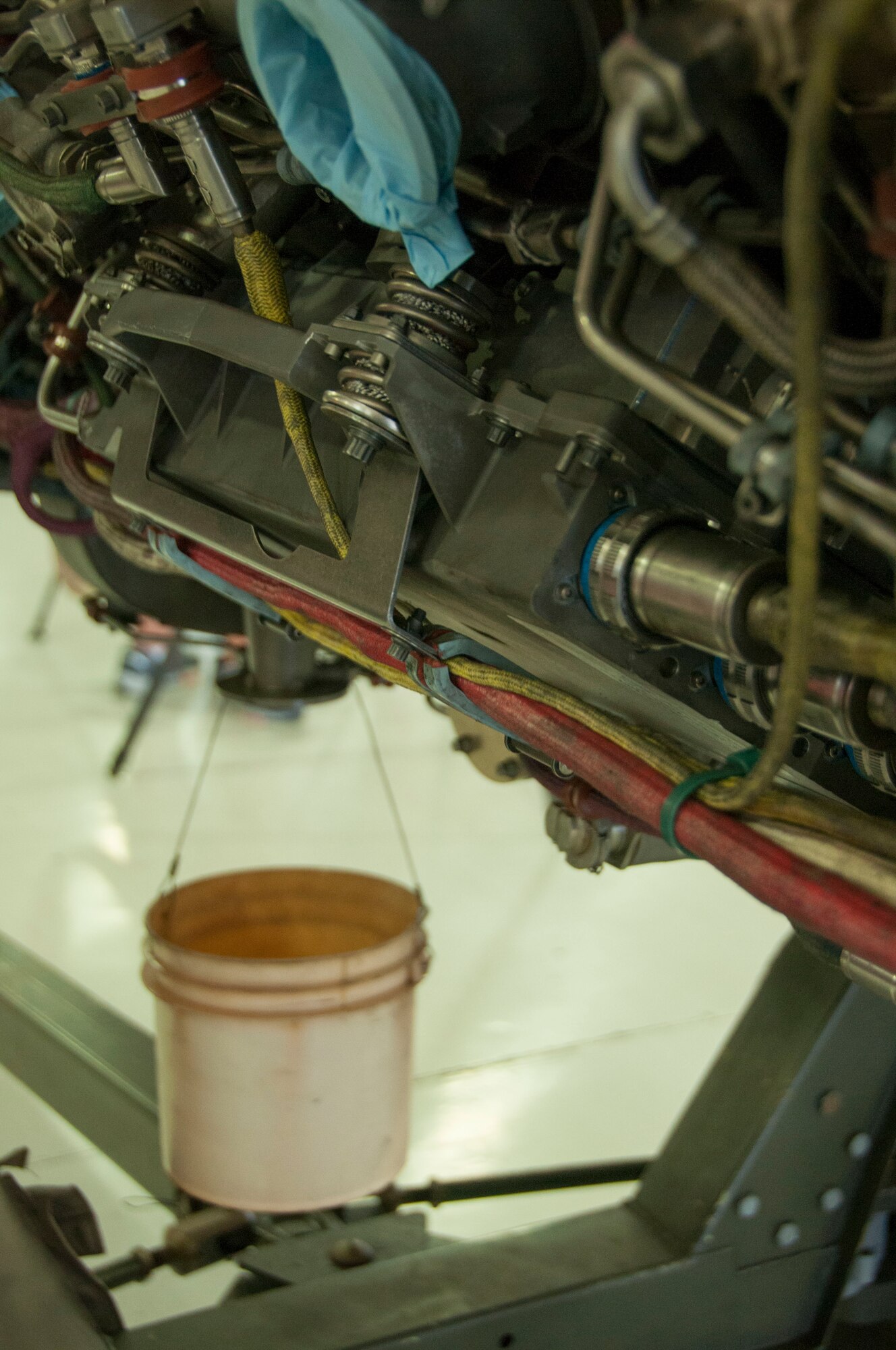 A bucket hangs off the bottom of an engine that has been removed from an F-16 for maintenance. Every drop of oil is gathered during the maintenance process to ensure clean aircraft and hangars, with the added benefit of being able to recycle the oil instead of traditional disposal. (Air National Guard photo by Capt. Logan Clark)