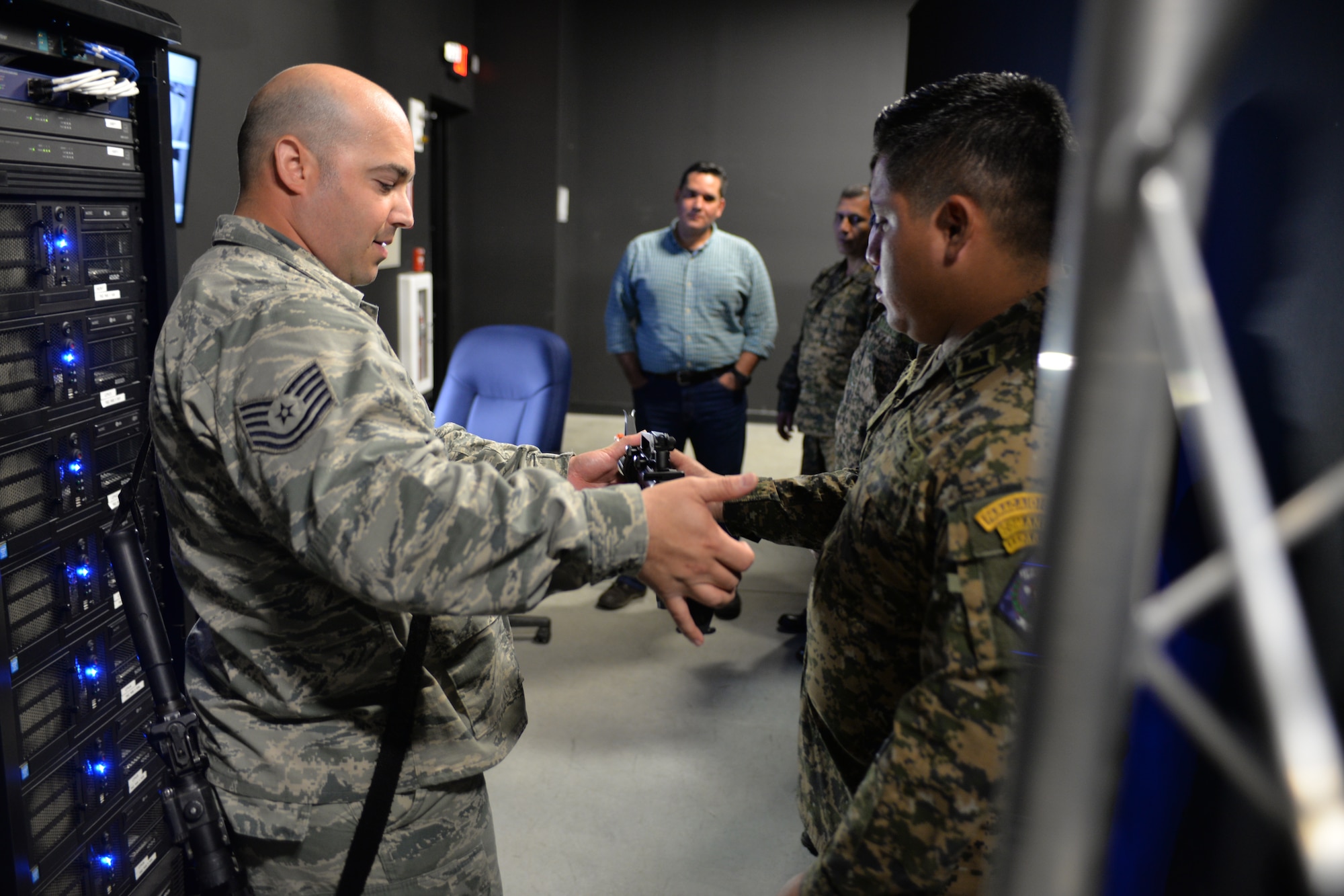 Tech. Sgt.  Angel Cardona, with the 157th Security Forces Squadron, New Hampshire Air National Guard, hands a shoot house laser simulator M-4 to LT. Elmer Edgardo Abrego Hernandez, with the El Salvador Armed Forces, during a state partnership program visit Aug. 4, 2016, at the New Hampshire National Guard Training Site, Center Strafford, N.H.(Air National Guard photo by Airman 1st Class Ashlyn J. Correia)