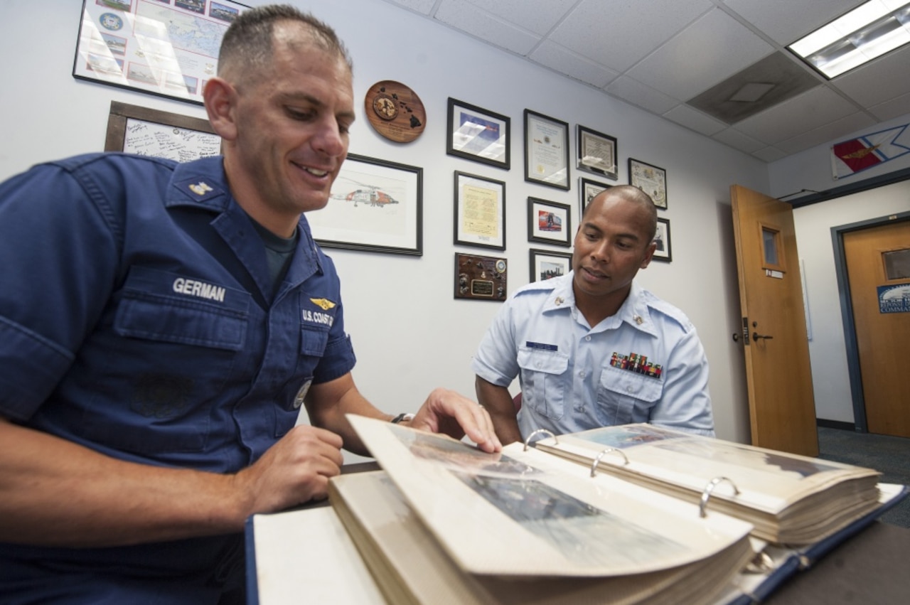 Coast Guard Command Master Chief Petty Officer Ronny German and Coast Guard Petty Officer 1st Class Kensley Raigeluw, look at old photos on Sand Island, Hawaii, Aug. 17, 2016. Raigeluw attributes the Coast Guard’s visit to his island of Woleai more than 20 years ago for the reason he decided to serve. Air Force photo by Staff Sgt. Christopher Hubenthal