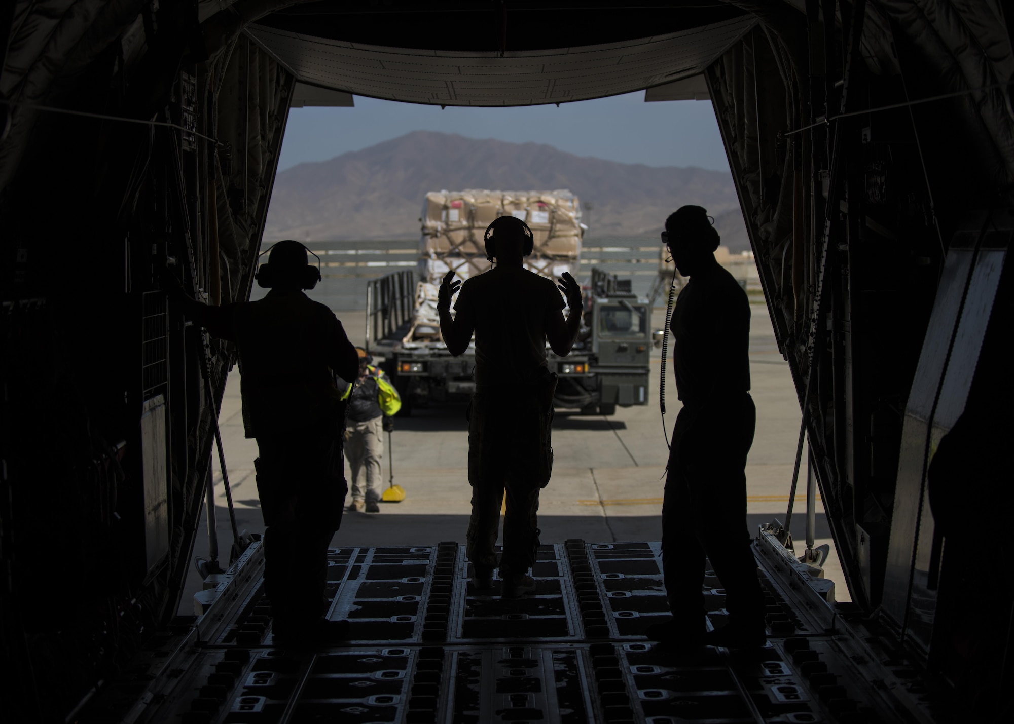 Senior Airman Andrew Garrett (center), 774th Expeditionary Airlift Squadron loadmaster, directs a 60k runner aircraft cargo loader, Bagram Airfield, Afghanistan, Aug. 19, 2016. Aircraft loadmasters are responsible for properly loading, securing and escorting cargo and passengers, and ensuring the plane is properly balanced with the weight of the cargo evenly distributed. (U.S. Air Force photo by Senior Airman Justyn M. Freeman)