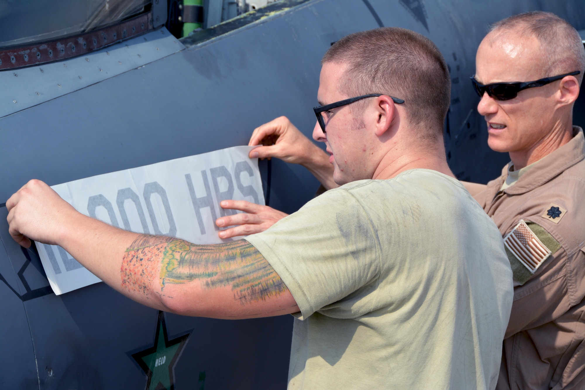 Senior Airman Bradley, 380th Expeditionary Aircraft Maintenance Squadron crew chief, and Lt. Col. Brandon, 335th Expeditionary Fighter Squadron commander, apply a 12,000 flying hour decal to the side of F-15E Strike Eagle #89-0487 after its milestone flight in an undisclosed location, Aug. 16, 2016. During the same flight, Brandon also achieved a career milestone of 3,000 flying hours after 25 years of service. (U.S. Air Force photo by Staff Sgt. Samantha Mathison)