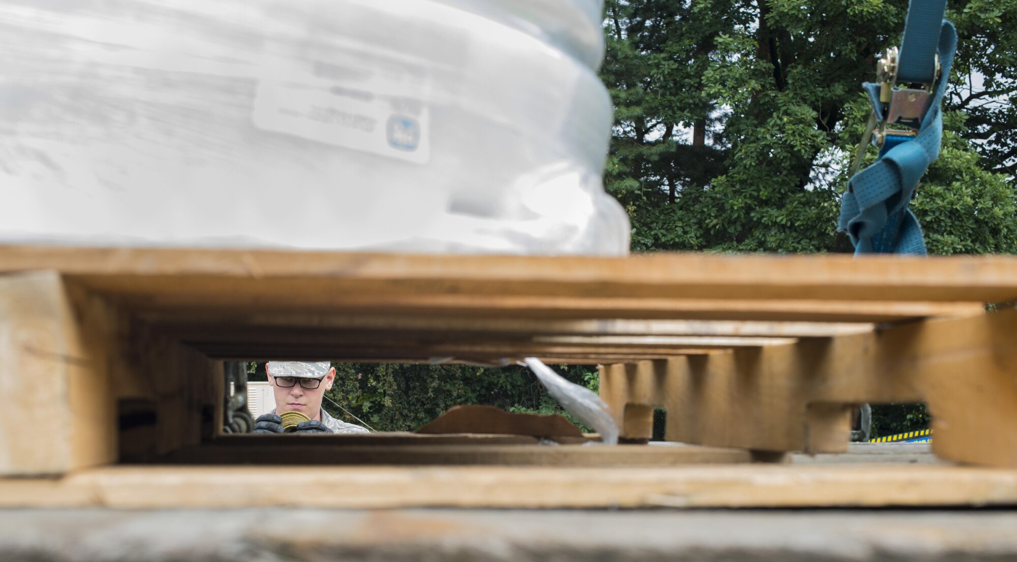 Airman 1st Class Brody Ellyson, 86th Vehicle Readiness Squadron vehicle operator, rolls the excess strap after securing a pallet to a flatbed Aug. 19, 2016 at Ramstein Air Base, Germany. Ellyson secured the strap to the pallet to ensure it does not get stuck in a wheel during transportation. (U.S. Air Force photo/Senior Airman Tryphena Mayhugh)
