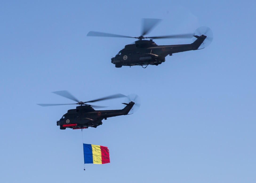 Two Romanian helicopters fly over a delighted crowd of spectators while carrying the Romanian flag during the 114th annual Navy Day celebration at the Port of Constanţa, Romania, Aug. 15, 2016. U.S. Sailors and Marines supporting the Black Sea Rotational Force 16.2 helped pay tribute to the prestigious history of the Romanian navy and highlighted the military’s movement toward new developments and modernizations. Black Sea Rotational Force is an annual multilateral security cooperation activity between the U.S. Marine Corps and partner nations in the Black Sea, Balkan and Caucasus regions designed to enhance participants’ collective professional military capacity, promote regional stability and build enduring relationships with partner nations. (U.S. Marine Corps photo by Sgt. Michelle Reif)