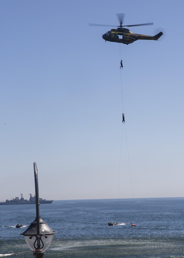 Two Romanian sailors hang suspended from a helicopter while a delighted crowd spectates during the 114th annual Navy Day celebration at the Port of Constanţa, Romania, Aug. 15, 2016. U.S. Sailors and Marines supporting the Black Sea Rotational Force 16.2 helped pay tribute to the prestigious history of the Romanian navy and highlighted the military’s movement toward new developments and modernizations. Black Sea Rotational Force is an annual multilateral security cooperation activity between the U.S. Marine Corps and partner nations in the Black Sea, Balkan and Caucasus regions designed to enhance participants’ collective professional military capacity, promote regional stability and build enduring relationships with partner nations. (U.S. Marine Corps photo by Sgt. Michelle Reif)
