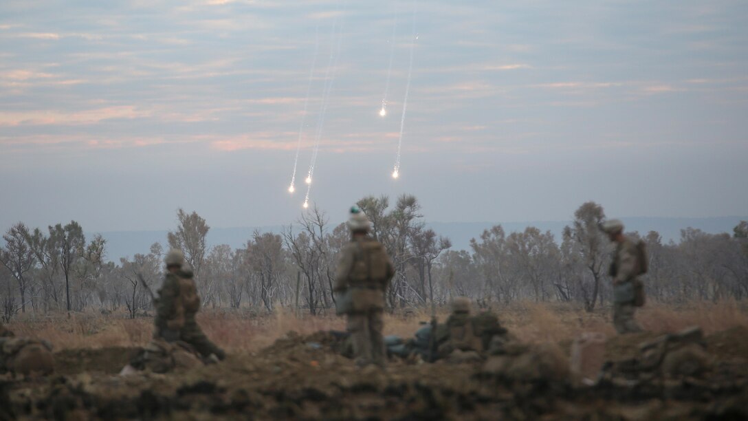 Marines with 1st Battalion, 1st Marine Regiment, watch illumination from artillery fall to the ground during a live fire range August 18, 2016, at Bradshaw Field Training Area, Northern Territory, Australia. The range was the final training evolution of Exercise Koolendong 16, a trilateral exercise between the U.S. Marine Corps, Australian Defence Force and French Armed Forces New Caledonia. Marines held a defensive position while engaging targets and working through the CS gas, which simulated a chemical attack.