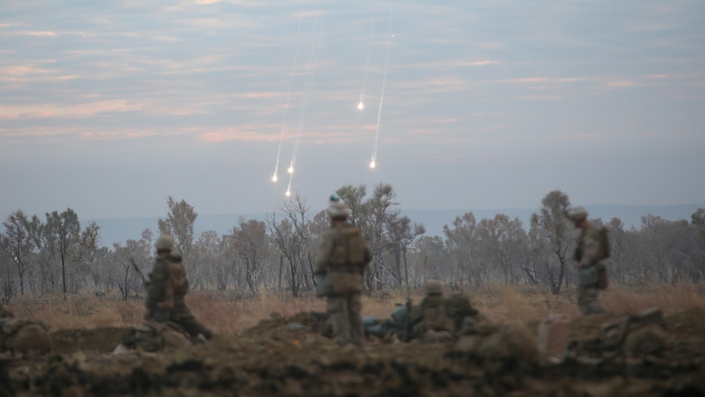 Marines with 1st Battalion, 1st Marine Regiment, watch illumination from artillery fall to the ground during a live fire range August 18, 2016, at Bradshaw Field Training Area, Northern Territory, Australia. The range was the final training evolution of Exercise Koolendong 16, a trilateral exercise between the U.S. Marine Corps, Australian Defence Force and French Armed Forces New Caledonia. Marines held a defensive position while engaging targets and working through the CS gas, which simulated a chemical attack.