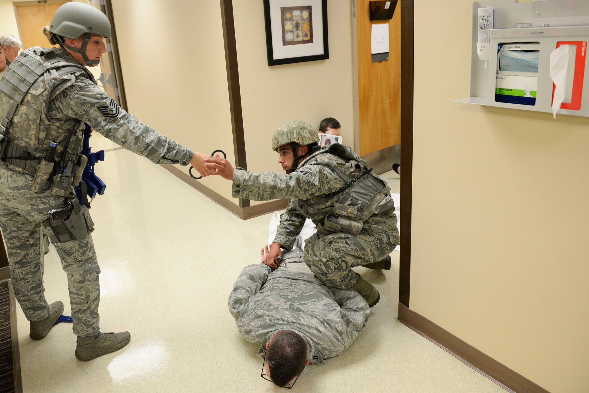 Tech. Sgt. Jessie Armstrong, 88th Security Forces Squadron patrolman, hands a pair of handcuffs to fellow patrolman Staff Sergeant Niko Valdez, during an active shooter exercise held inside the hospital on Wright-Patterson Air Force Base, Ohio, August 4, 2016. Security Forces are responsible for clearing the building and escorting medical personnel to attend to victims. (U.S. Air Force photo / Wesley Farnsworth)