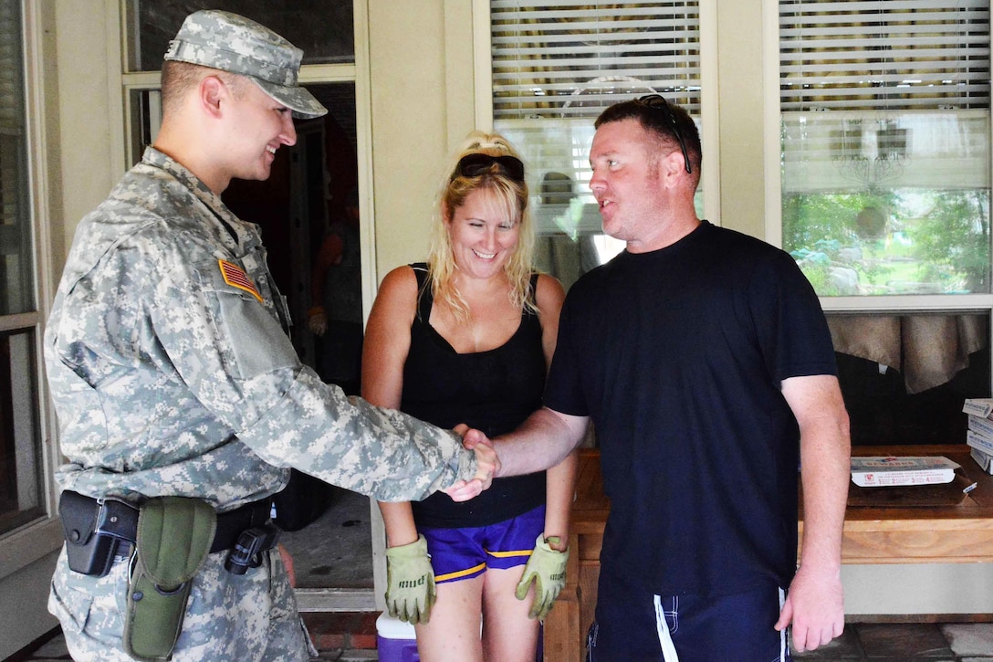 Army Spc. William J. George, left, talks to Army Maj. Brent J. Lewis, and his wife, Venessa, residents of the flood-stricken Greystone Subdivision in Denham Springs, La., Aug. 19, 2016. George, a police officer assigned to the Louisiana National Guard's 39th Military Police Company, 773rd MP Battalion, 139th Regional Support Group, was conducting a roving patrol of the area to ensure safety and security in the area. Army National Guard photo by Staff Sgt. Scott D. Longstreet 