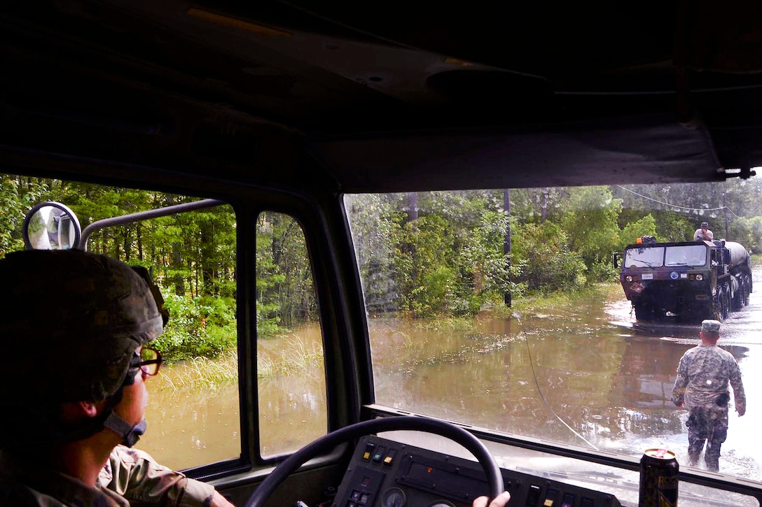 Army Lt. Col. Cameron Magee ground guides a vehicle through high water in flood-stricken Gonzales, La., Aug. 19, 2016. More than 30 inches of rainfall caused severe flooding in many portions of southeast Louisiana. Magee is commander, Louisiana National Guard's 2nd Squadron, 108th Cavalry Regiment. Army National Guard photo by Sgt. Noshoba Davis